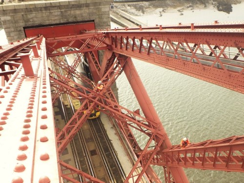 Image of maintenance work by Network Rail on the Forth Bridge, looking down on a train